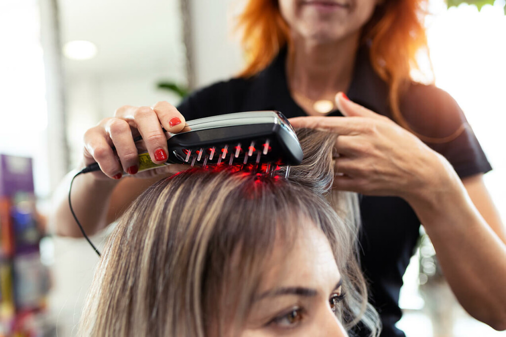 Laser hair therapy brush applied to a woman’s head at a hair clinic