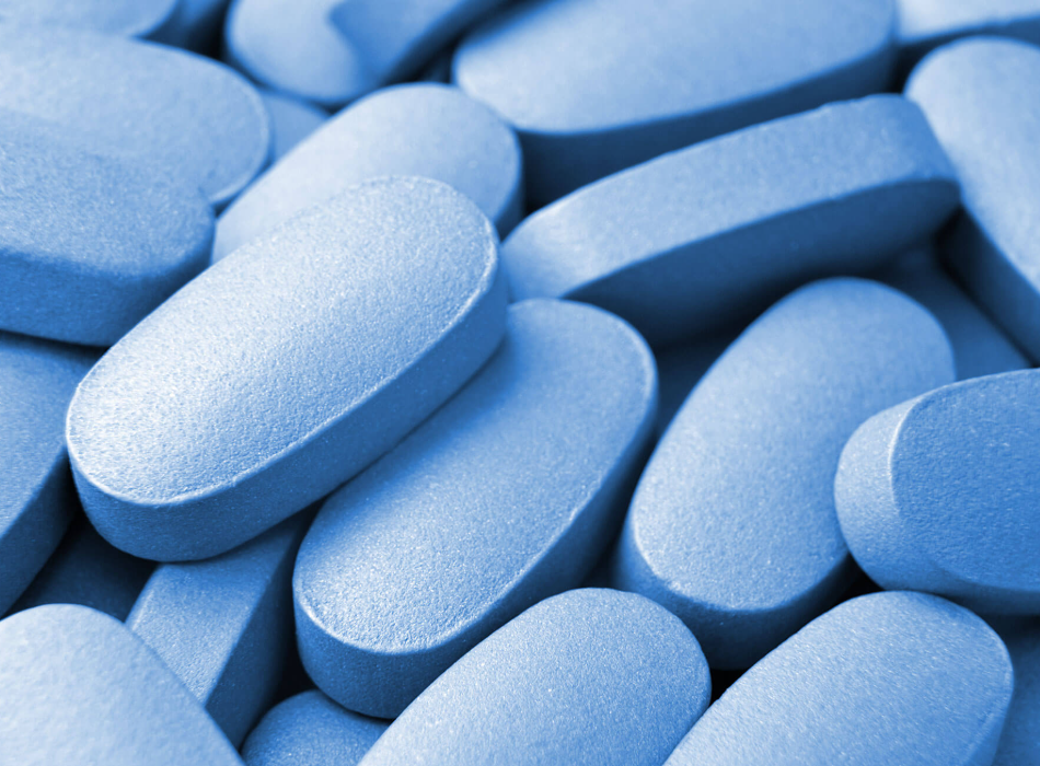 Close-up of blue tablets representing oral DHT blocker supplements used to treat hair loss.